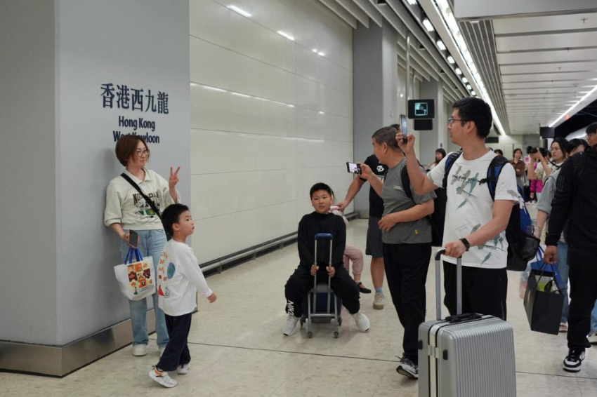 5月1日，乘客乘坐北京西-香港西九龙G79次列车抵达香港西九龙站后与站牌合影。